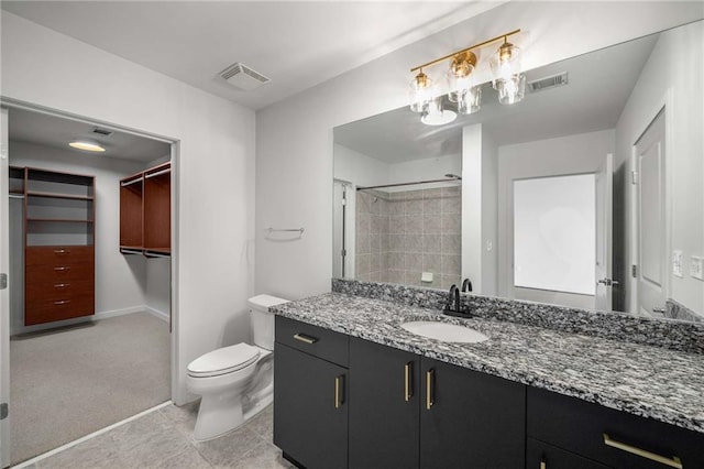 bathroom featuring toilet, vanity, a shower, a walk in closet, and baseboards