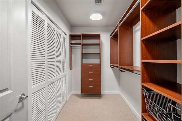 walk in closet with light carpet