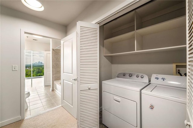 clothes washing area with washing machine and clothes dryer, light colored carpet, and baseboards