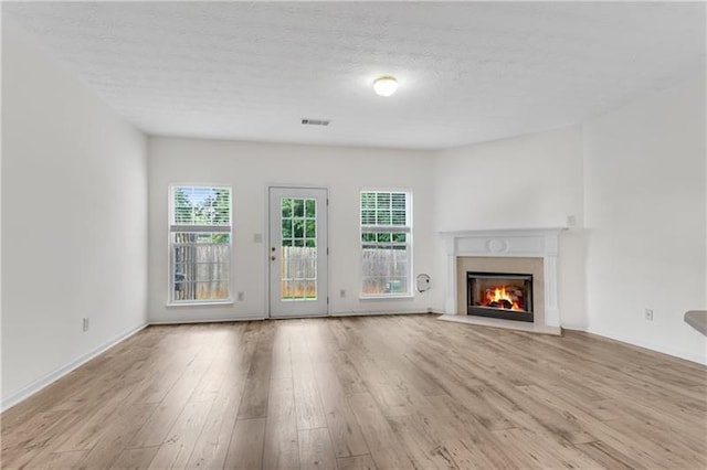 621 Kenridge Way Unit 0, Suwanee, GA 30024 - unfurnished living room with wood finished floors, a warm lit fireplace, healthy amount of natural light, and a textured ceiling