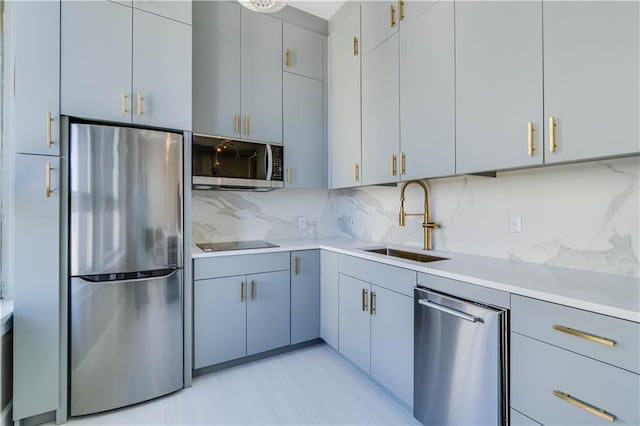 kitchen with tasteful backsplash, stainless steel appliances, light countertops, and a sink