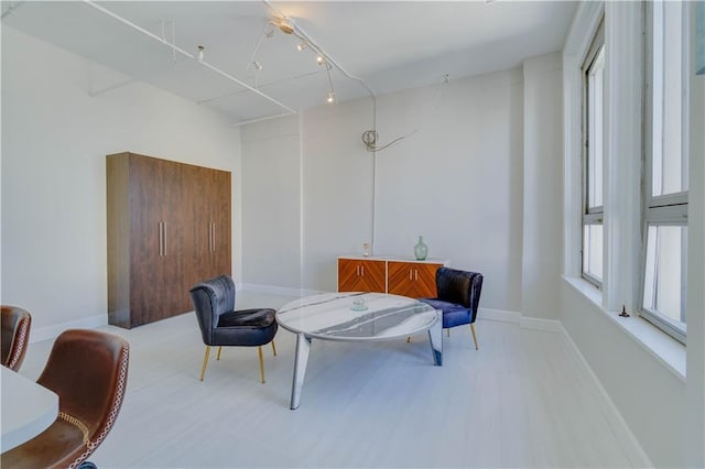 living area with baseboards, wood finished floors, and track lighting