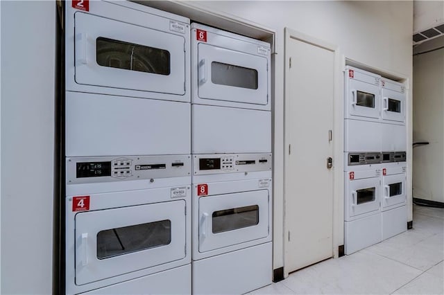 common laundry area featuring light tile patterned floors, visible vents, and stacked washer / drying machine