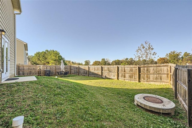 view of yard featuring a fenced backyard and a fire pit