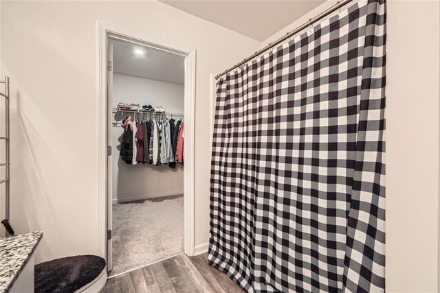 full bathroom featuring wood finished floors, a walk in closet, and toilet