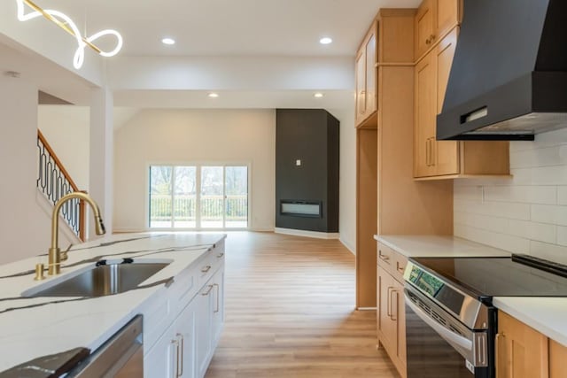 kitchen featuring wall chimney range hood, sink, light hardwood / wood-style flooring, hanging light fixtures, and electric range