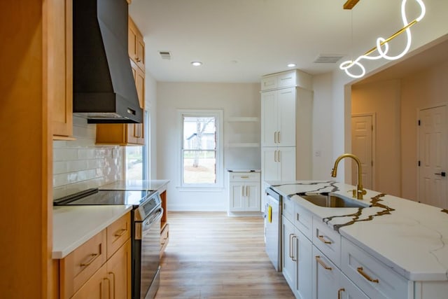 kitchen with wall chimney exhaust hood, sink, white cabinetry, stainless steel range with electric stovetop, and decorative light fixtures