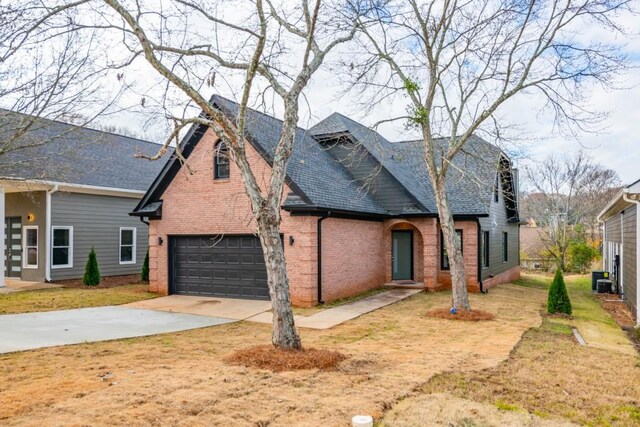 view of front of home featuring cooling unit, a garage, and a front lawn