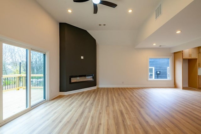 unfurnished living room featuring vaulted ceiling, a large fireplace, ceiling fan, and light hardwood / wood-style flooring