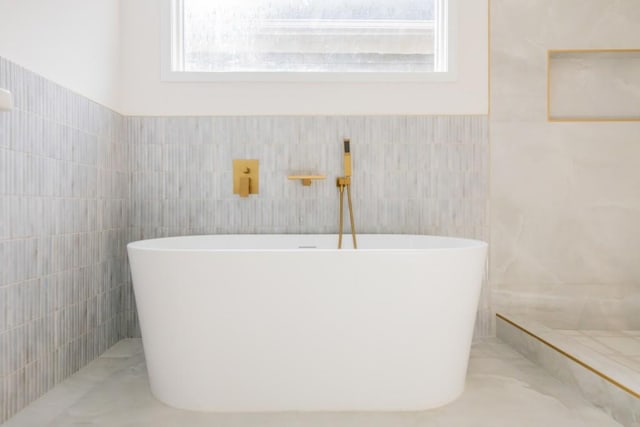 bathroom with tile walls and a bathtub