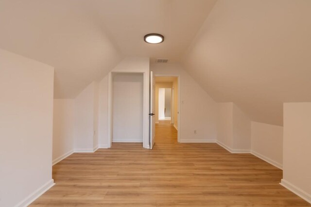 additional living space featuring lofted ceiling and light wood-type flooring