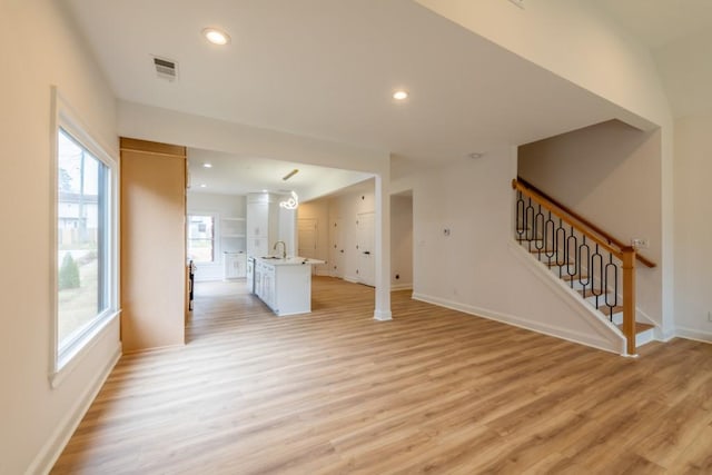 unfurnished living room featuring sink and light hardwood / wood-style flooring