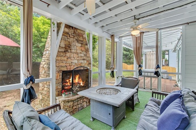 sunroom with ceiling fan, beamed ceiling, and an outdoor living space with a fireplace