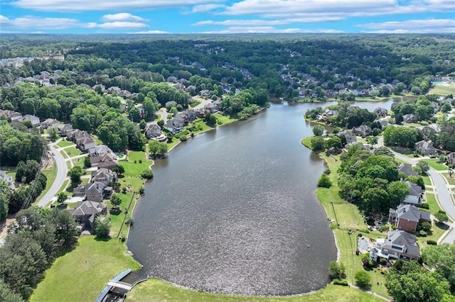 aerial view of property's location with a large body of water, a forest, and nearby suburban area