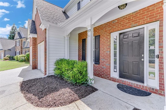 property entrance featuring brick siding, a shingled roof, and a porch