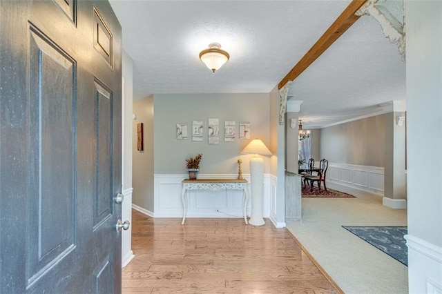 entryway featuring a decorative wall, a chandelier, wainscoting, wood finished floors, and a textured ceiling