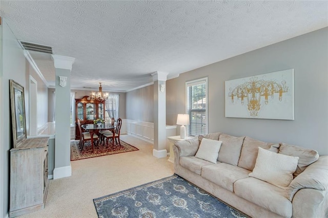 carpeted living room with a chandelier, a textured ceiling, ornamental molding, and a wainscoted wall