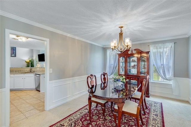 dining space with a chandelier, plenty of natural light, wainscoting, light colored carpet, and ornamental molding