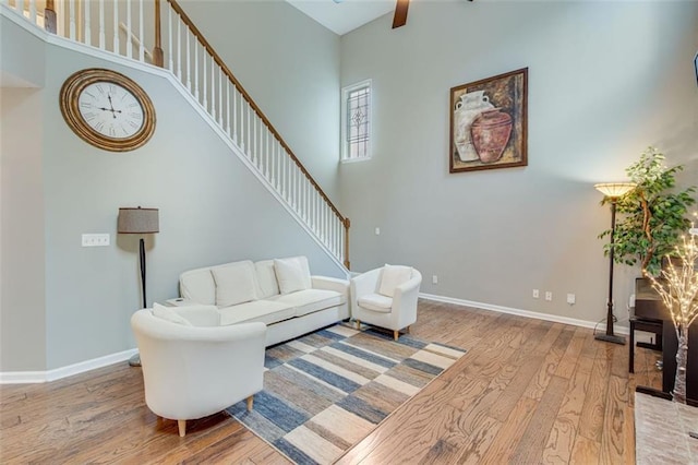 living area with wood finished floors, stairs, baseboards, and a towering ceiling