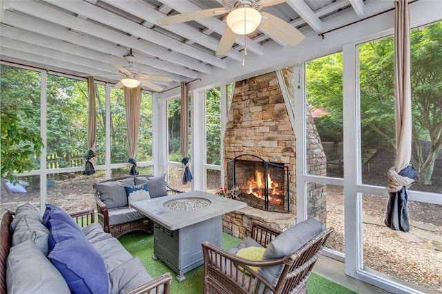 sunroom / solarium with a ceiling fan, an outdoor living space with a fireplace, and beamed ceiling
