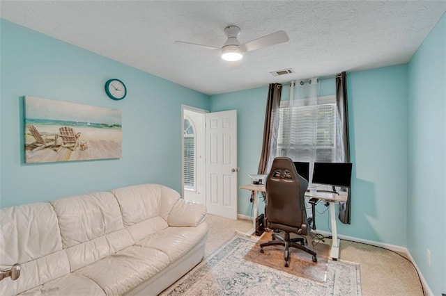 office space featuring carpet, baseboards, a ceiling fan, and a textured ceiling