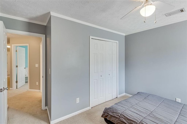 carpeted bedroom with ornamental molding, a textured ceiling, a closet, baseboards, and ceiling fan