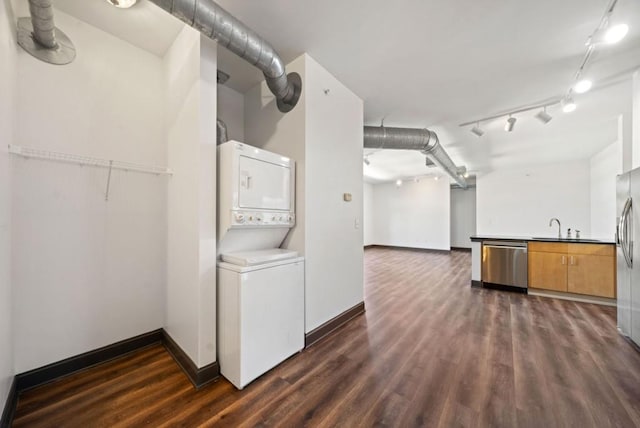 clothes washing area with laundry area, baseboards, dark wood-style flooring, stacked washing maching and dryer, and a sink