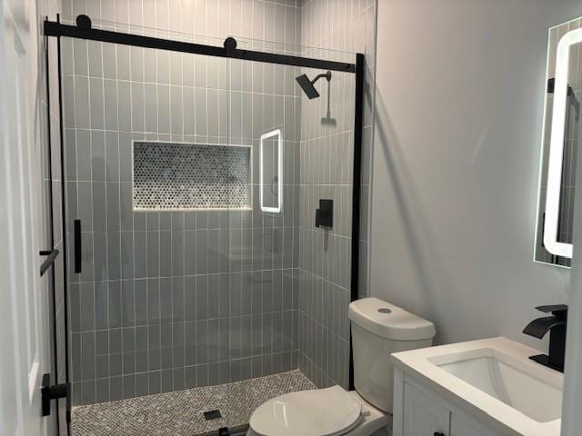 bathroom featuring vanity, toilet, and a shower with door