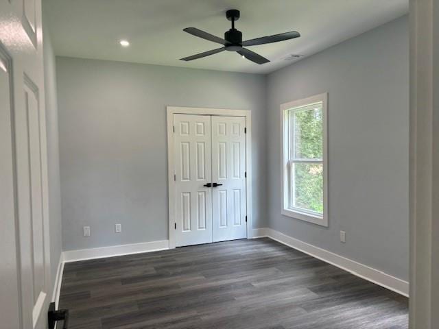 unfurnished bedroom with dark hardwood / wood-style flooring, a closet, and ceiling fan