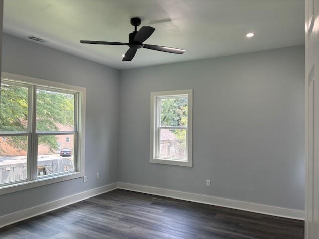 empty room featuring dark wood-type flooring and ceiling fan