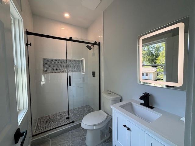 bathroom with vanity, tile patterned floors, a shower with door, and toilet