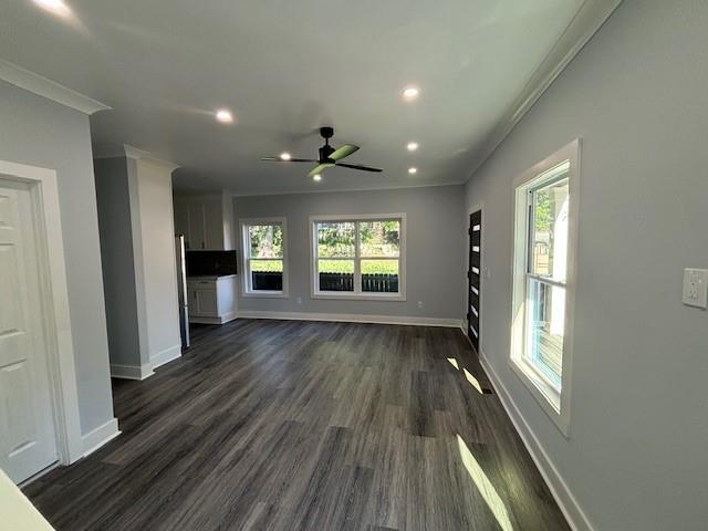 unfurnished living room featuring crown molding, dark wood-type flooring, and ceiling fan