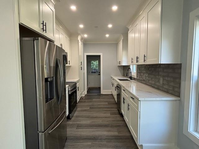 kitchen featuring light stone counters, decorative backsplash, stainless steel appliances, and white cabinets