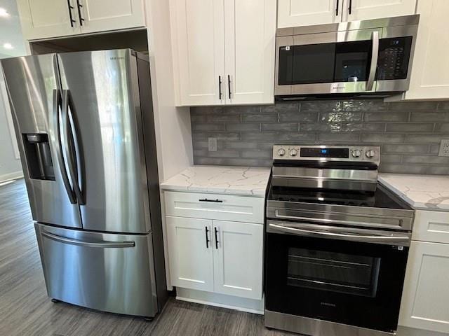 kitchen featuring white cabinetry, appliances with stainless steel finishes, light stone counters, and decorative backsplash