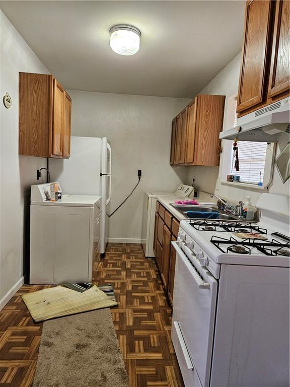 kitchen with washer / clothes dryer, dark parquet flooring, sink, and white appliances