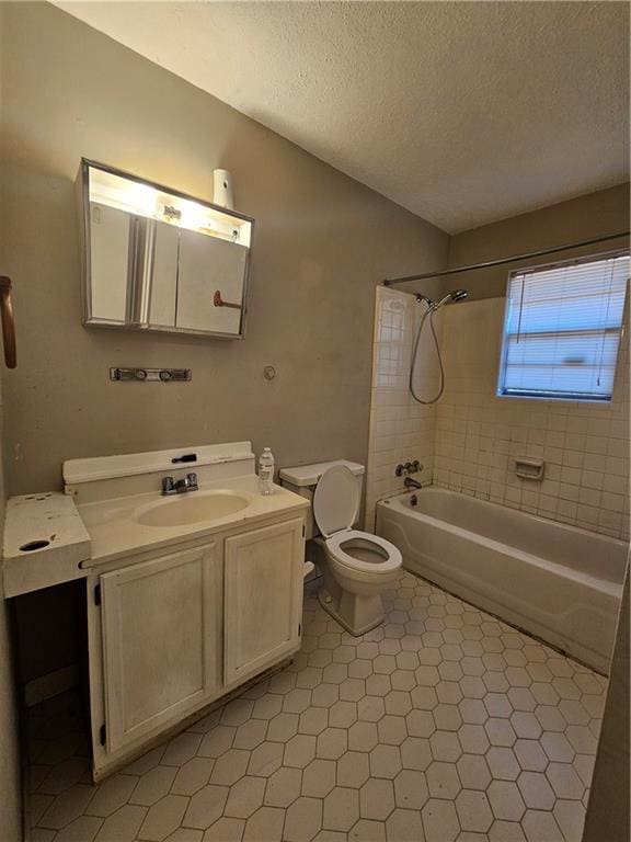 full bathroom with tiled shower / bath combo, vanity, a textured ceiling, and toilet