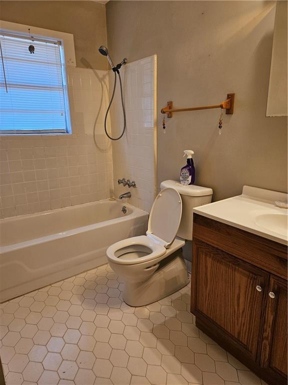 full bathroom featuring tile patterned floors, vanity, toilet, and tiled shower / bath combo