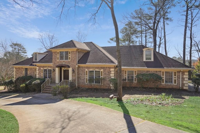 view of front facade featuring brick siding and roof with shingles