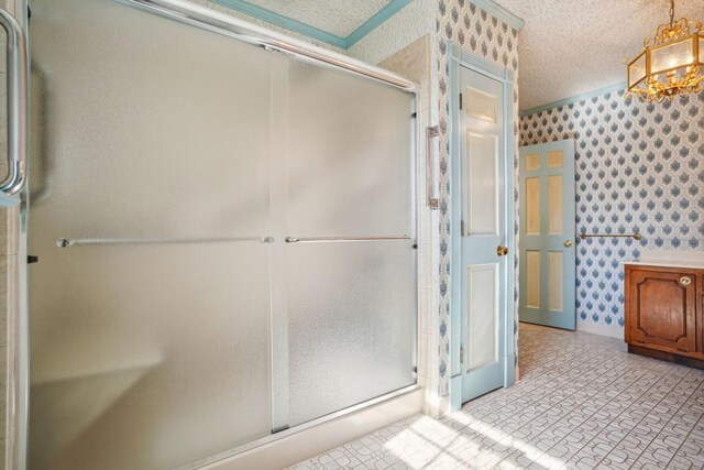 bathroom with a shower stall, a textured ceiling, and wallpapered walls