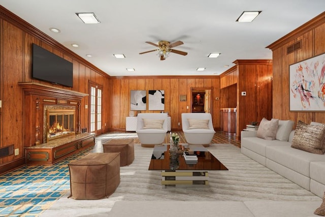 living area featuring a premium fireplace, visible vents, wooden walls, and ornamental molding