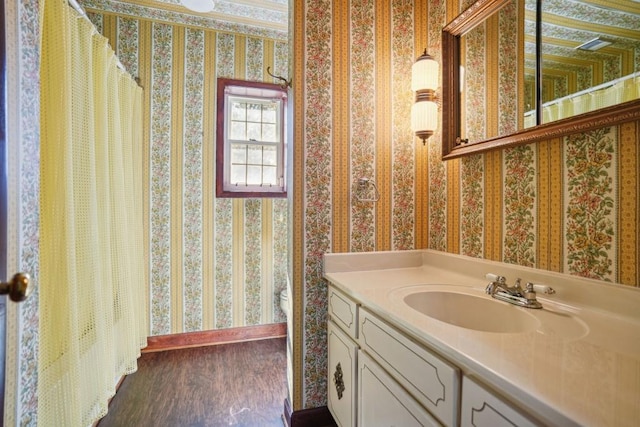 full bath featuring baseboards, wood finished floors, vanity, and wallpapered walls