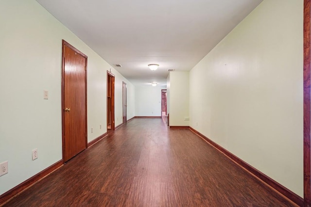 unfurnished room featuring baseboards and dark wood finished floors