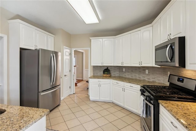 kitchen with light tile patterned floors, stainless steel appliances, tasteful backsplash, and white cabinets