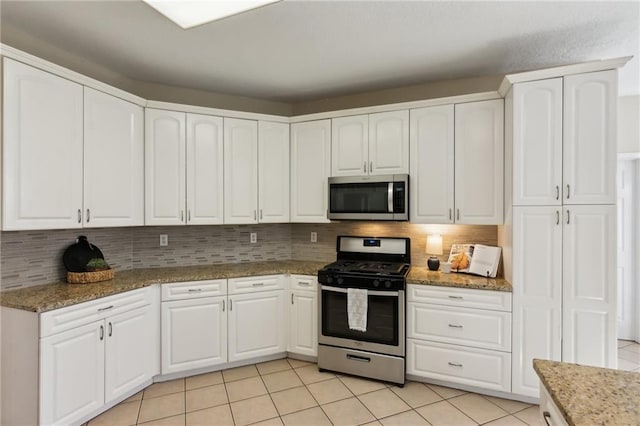 kitchen with light stone countertops, light tile patterned floors, stainless steel appliances, and decorative backsplash