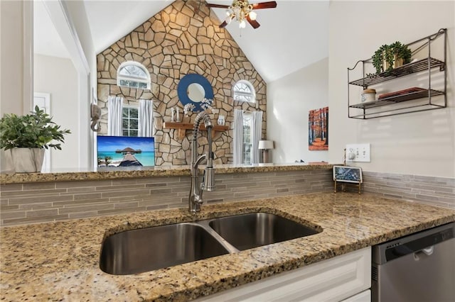 kitchen with light stone counters, a sink, a ceiling fan, white cabinetry, and stainless steel dishwasher