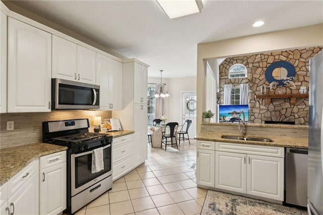 kitchen with light tile patterned floors, white cabinets, a sink, stainless steel appliances, and backsplash