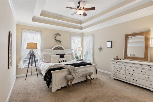 bedroom featuring ceiling fan, light carpet, baseboards, ornamental molding, and a tray ceiling