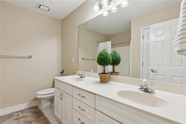 bathroom with visible vents, a sink, toilet, and double vanity