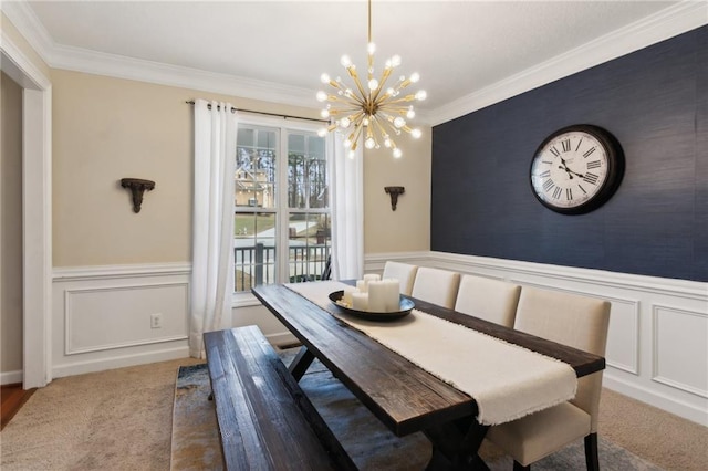 dining room with an accent wall, ornamental molding, carpet flooring, and wainscoting