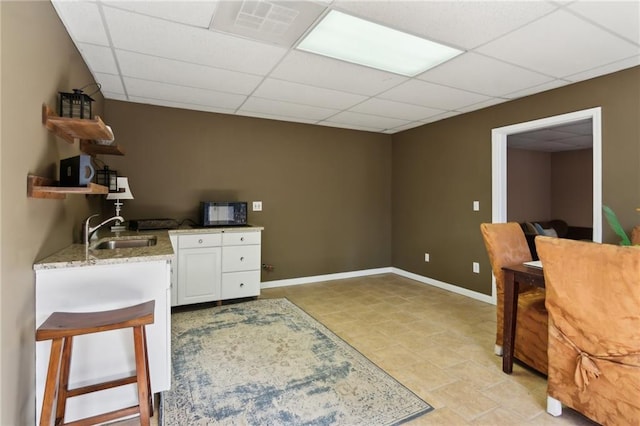 office space featuring visible vents, a sink, a paneled ceiling, and baseboards